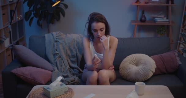 View from above of young uptight woman sitting on sofa and holding positive pregnancy test. Millennial upset girl being worried about unplaned gestation. Concept of unwanted pregnancy. - 映像、動画