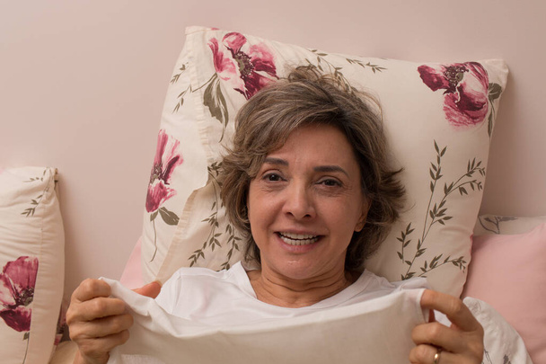 Γυναίκα άρρωστη στο κρεβάτι με τη γρίπη φυσώντας τη μύτη της σε ένα μαντήλι - Φωτογραφία, εικόνα