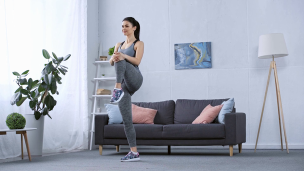 Attractive sportswoman stretching legs at home  - Felvétel, videó