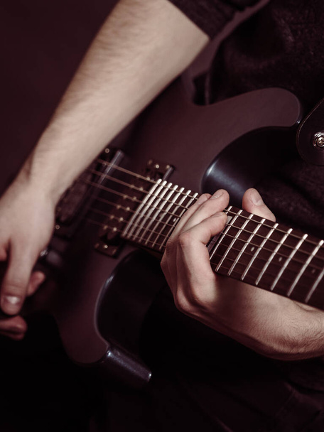 Male hands with electric guitar. Close up, part body adult person is holding instrument and playing. Hobby, music concept - Фото, зображення