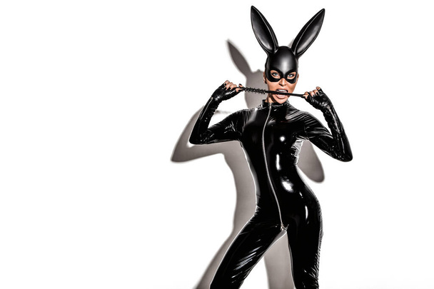 Sexy blonde beautiful woman posing in latex costume and black bunny mask on white background. Easter bunny concept. - 写真・画像