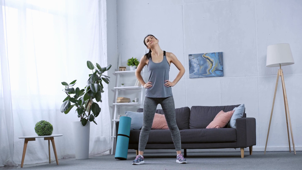 Schöne Sportlerin wärmt sich im Wohnzimmer auf - Filmmaterial, Video