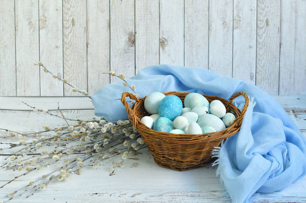 blue Easter eggs in a wicker basket and bouquet of willow flowers on light background.Naturally Eggs painted with hibiscus with marble stone effect. Eco paint. Happy Easter card.Selective focus. - Photo, Image