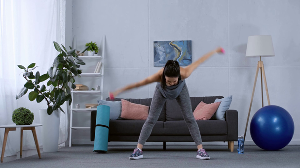 Sportlerin trainiert mit Hanteln im Wohnzimmer - Filmmaterial, Video