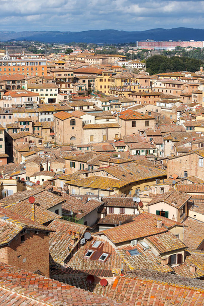 シエナ、中世の町、イタリアのトスカーナ州のシエナ州の首都の屋根の上の空中ビュー - 写真・画像