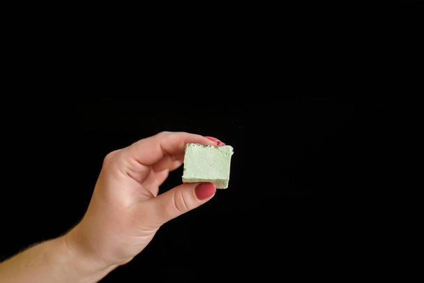 In Frauenhänden ist die Knautschzone ein Stück Marshmallows. Nahaufnahme eines köstlichen Desserts - Foto, Bild