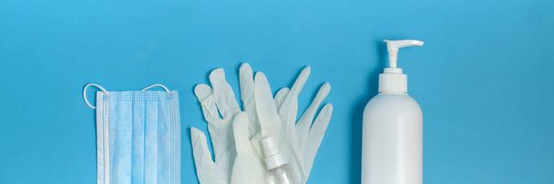 Seife, Antiseptikum, Handschuhe und Maske auf blauem Hintergrund. Virenschutzkonzept. Banner - Foto, Bild