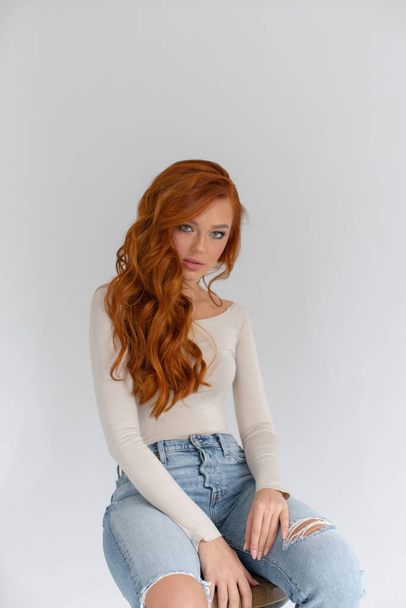 Jeune fille aux cheveux roux en jeans et un body dans un roo lumineux
 - Photo, image