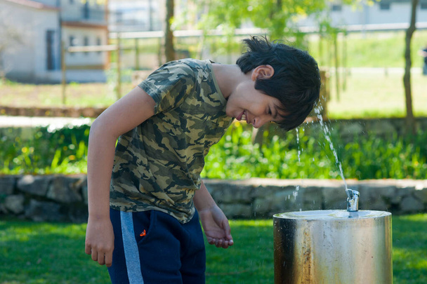 bagnato giovane ragazzo carino rinfrescarsi con acqua in una giornata di sole nel parco
  - Foto, immagini