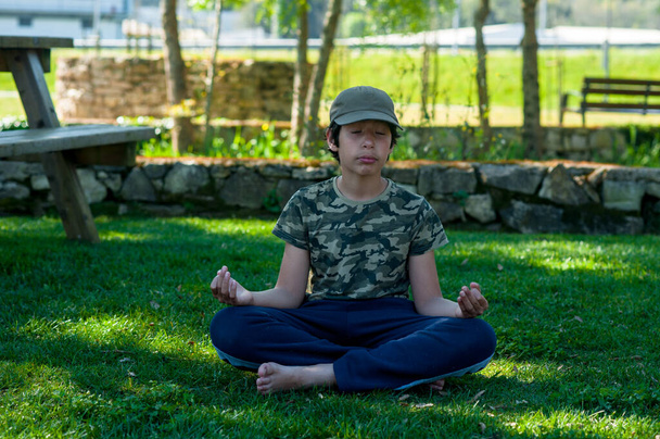 kleiner netter Junge praktiziert Yoga in einem Park an einem sonnigen Tag. - Foto, Bild