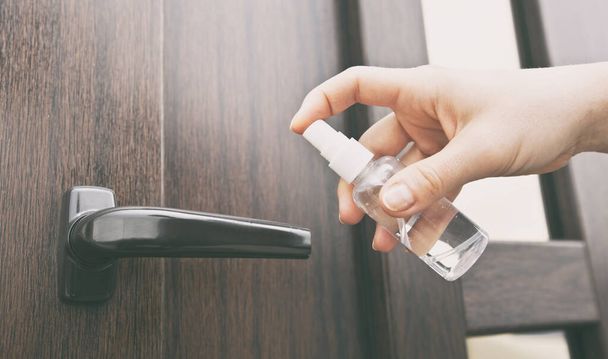 The wooman is applying sanitizer on the door handle - 写真・画像