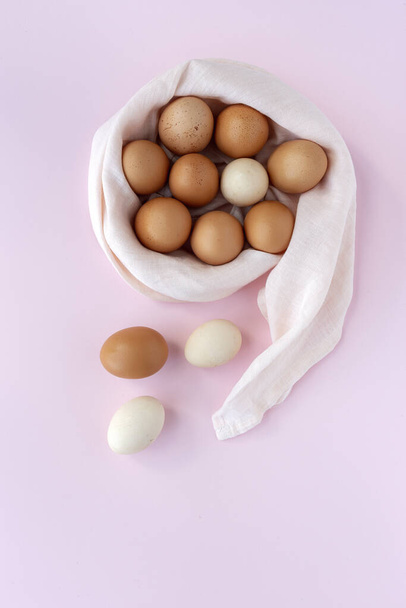 Huevos de gallina frescos de dos colores sobre fondo rosa desde arriba.
 - Foto, Imagen