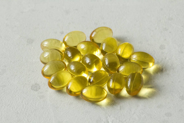 Kasa läpinäkyviä kapseleita kullankeltainen väri sijaitsee vaaleanharmaa moderni tausta. Öljy kapselit A-vitamiini, D3-vitamiini, kalaöljy, omega 3, 6, 9, ilta primrose, D-vitamiini, E-vitamiini
. - Valokuva, kuva