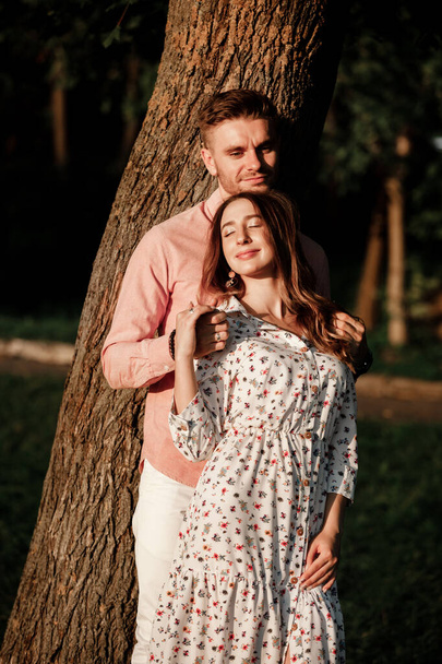 beautiful young couple in love hugging and smiling in the summer park. Stylish man in pink shirt and woman in dress are having fun together. love story. copy space. - Foto, Bild