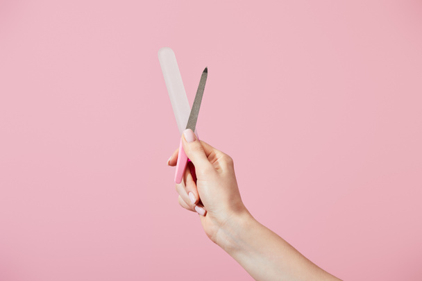 Gesneden weergave van vrouwelijke hand met nagel bestanden geïsoleerd op roze - Foto, afbeelding