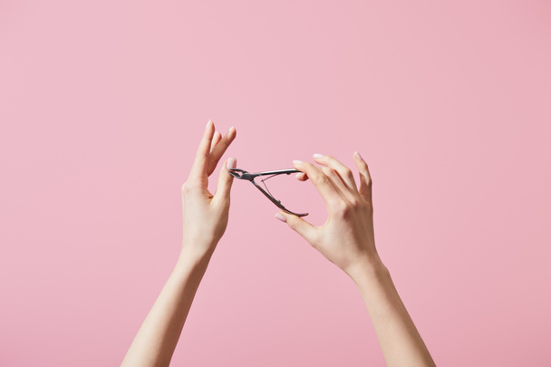 Cropped view of woman cutting cuticle with nipper isolated on pink - Fotoğraf, Görsel