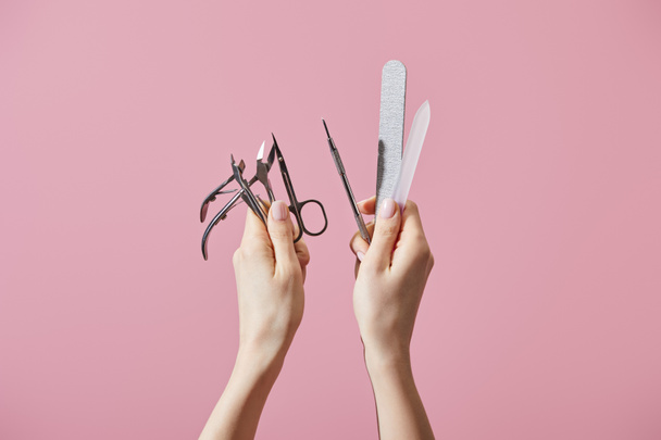 Gewassen beeld van vrouw met manicure instrumenten geïsoleerd op roze - Foto, afbeelding