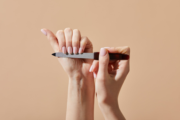 Cropped view of woman filing nails isolated on beige - Photo, Image