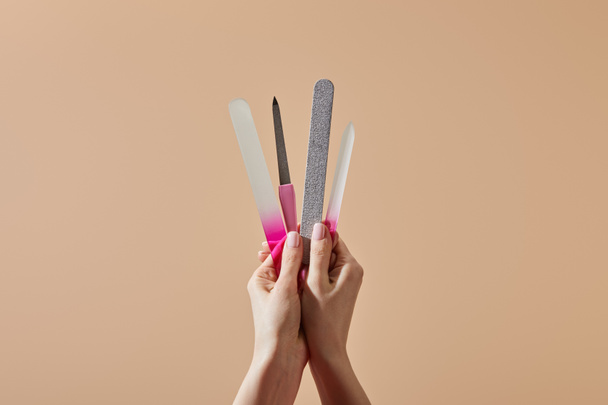 Cropped view of woman holding nail files and emery board isolated on beige - Photo, image