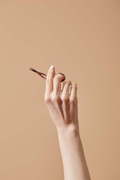 Cropped view of female hand with nail scissors isolated on beige - Foto, Imagem