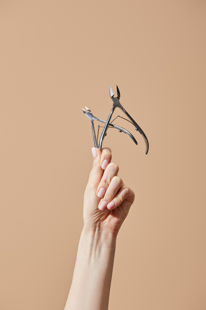Cropped view of female hand with cuticle nippers isolated on beige - Photo, image