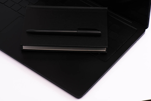 portátil negro y pluma en el teclado portátil aislado en blanco
  - Foto, Imagen