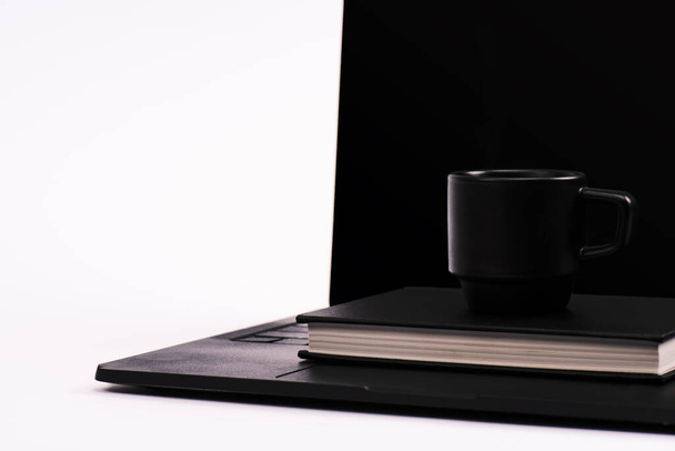 black notebook and cup on laptop with blank screen isolated on white  - Foto, afbeelding