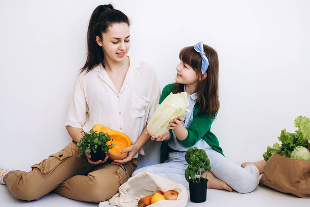 Auspacken einer Öko-Tüte mit frischem Gemüse und Gemüse nach dem Einkauf durch zwei Mädchen. Konzept der gesunden Ernährung. - Foto, Bild