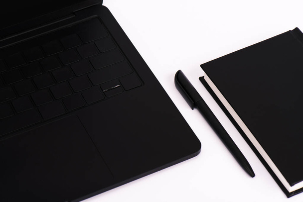 στυλό και σημειωματάριο κοντά στο σύγχρονο φορητό υπολογιστή που απομονώνονται σε λευκό  - Φωτογραφία, εικόνα