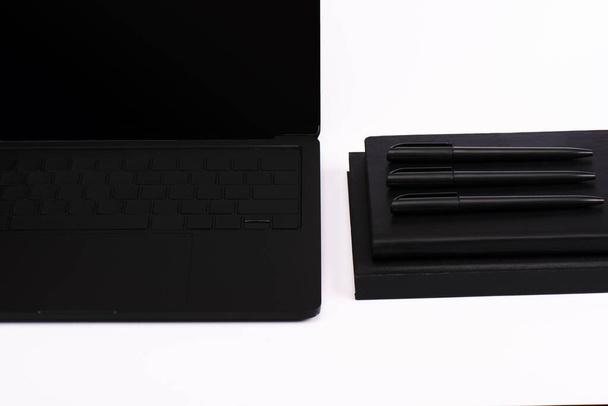 Stifte und Notizbücher in der Nähe von modernen Laptops mit leerem Bildschirm isoliert auf weiß  - Foto, Bild
