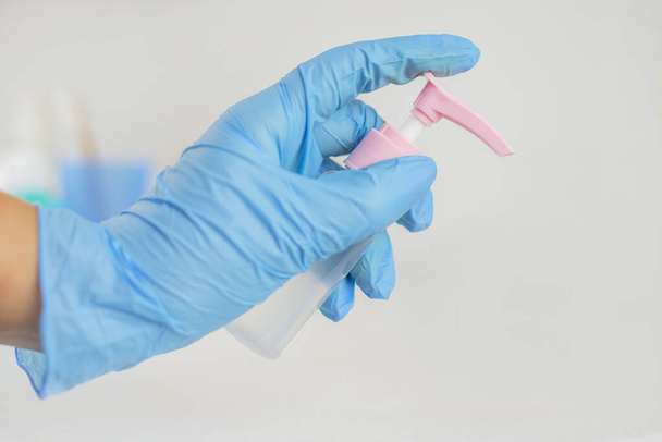 антибактериальный антисептик в руках девушки в синих перчатках против инфекций и микробов
 - Фото, изображение