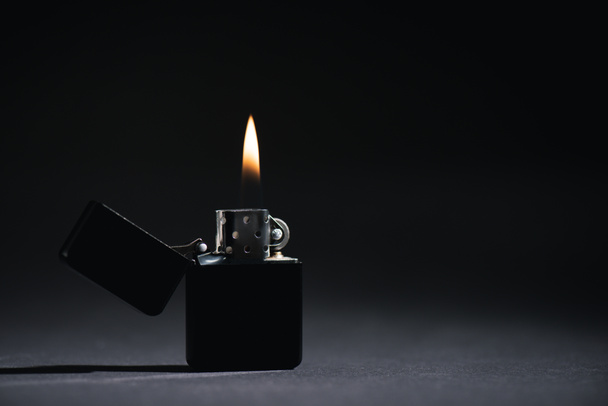zapalovač s hořícím ohněm na černé s kopírovacím prostorem  - Fotografie, Obrázek