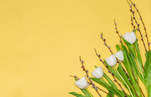 Bouquet of white tulips and pussy-willow branches on a yellow background, copy space, flat lay. Place for text. The concept of the holiday, spring. View from above. - Φωτογραφία, εικόνα