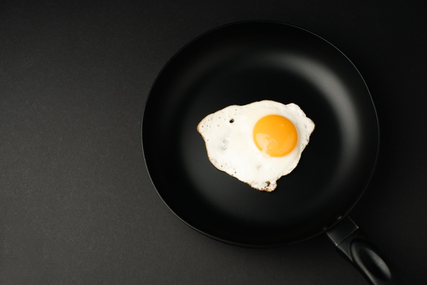 вид сверху на жареное яйцо на сковороде, изолированный на черном
  - Фото, изображение
