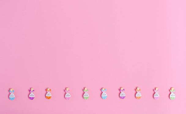 Decorative easter clothespins for decor on a pink background, copy space, flat lay. Place for text. The concept of the holiday, spring. View from above. Horizontal orientation. - Фото, изображение