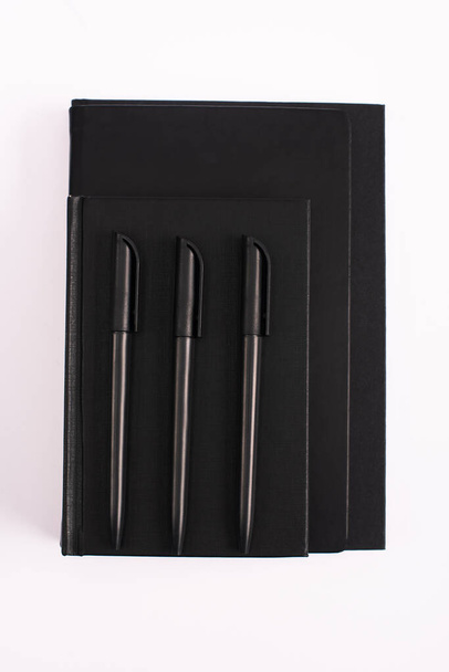 vista superior de bolígrafos en libros de copia en negro aislados en blanco
  - Foto, Imagen