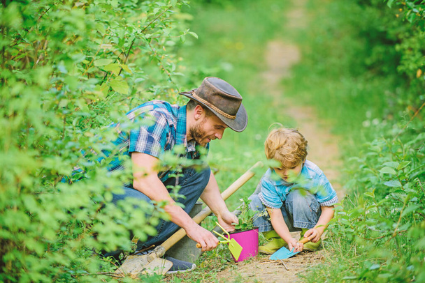 Gardening tools. Gardening hobby. Dad teaching little son care plants. Spring gardening routine. Planting flowers. Little helper in garden. Farm family. Little boy and father in nature background - Photo, Image