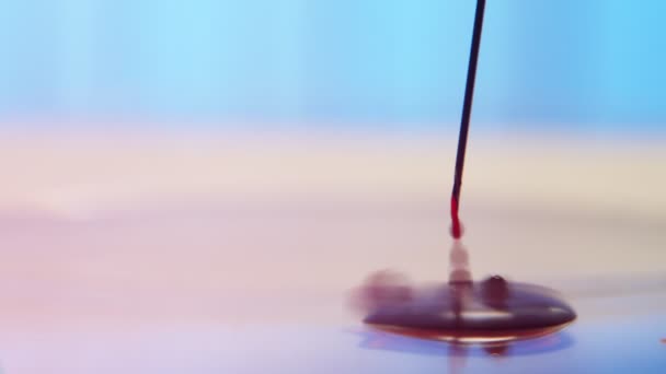Krople krwi tryskające na gładkiej powierzchni kształtującej basen w nowoczesnym laboratorium Artystyczne zbliżenie czerwonych kropli krwi rozlewających się z metalowej igły na gładką powierzchnię w celu przetestowania koronawirusu i utworzenia małej kałuży w nowoczesnym laboratorium.  - Materiał filmowy, wideo