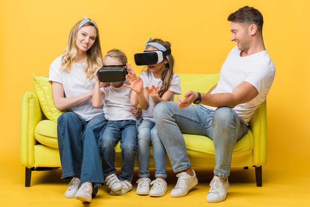 happy parents with children in virtual reality headsets sitting on sofa on yellow   - Photo, image