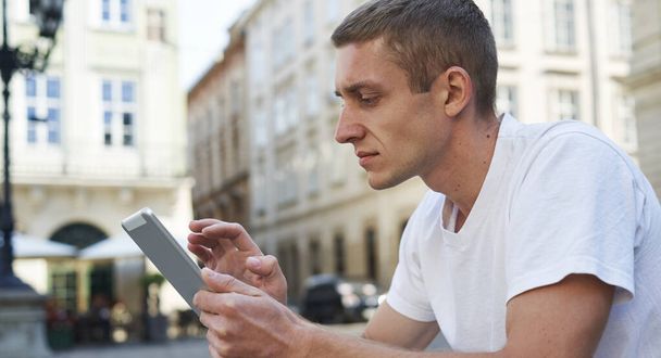 δημιουργικός άνθρωπος κάθεται στο πεζοδρόμιο και χρησιμοποιώντας το tablet υπολογιστή - Φωτογραφία, εικόνα