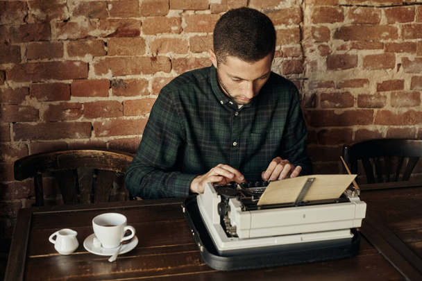 Young man writing on old typewriter. - Fotografie, Obrázek