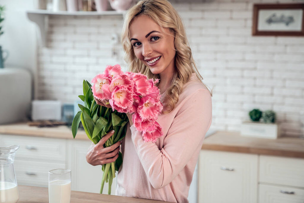 Menina encantadora bonito com um buquê de flores de tulipa apresentado por sua filha na cozinha
 - Foto, Imagem