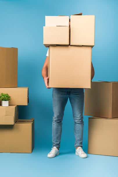 man holding cardboard boxes for relocation on blue  - Photo, Image