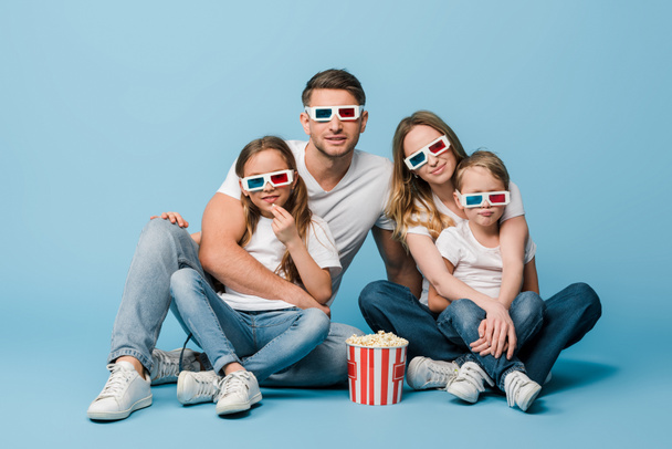 heureux famille regarder film en 3d lunettes avec seau de maïs soufflé sur bleu
 - Photo, image