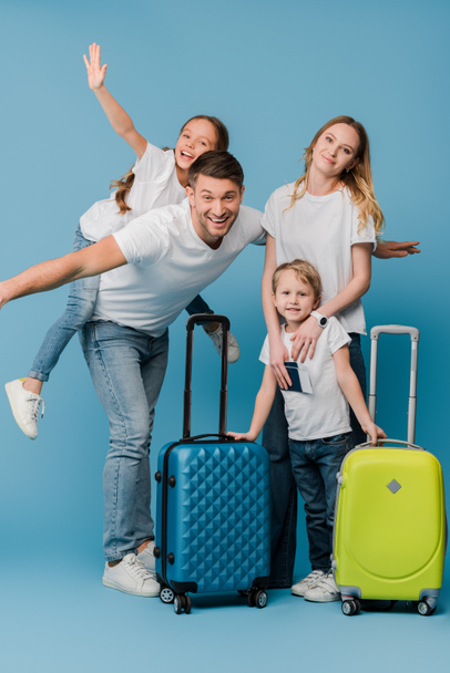 izgatott utazók családja bőröndökkel, útlevelekkel és kék jegyekkel - Fotó, kép