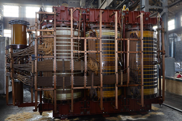 Trójfazowy transformator wysokiego napięcia podczas remontu w fabryce. Transformator uzwojeniowy - Zdjęcie, obraz