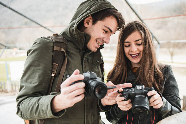 Beautiful, young couple of photographers with their cameras. Girlfriend showing photos to her boyfriend - Foto, Imagem