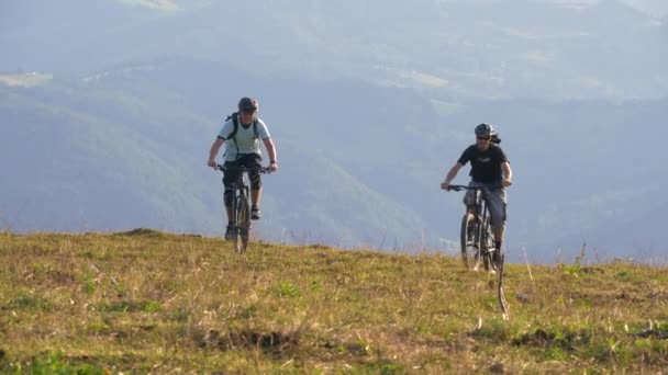 Due amici pedalano le loro mountain bike su una collina durante un'avventura in bicicletta
. - Filmati, video