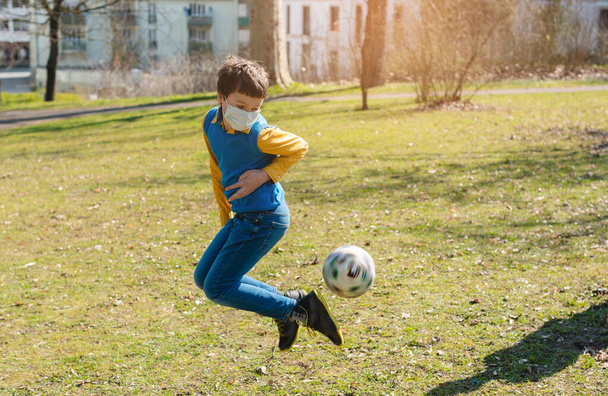Junge spielt trotz Covid-19-Krise Fußball im Park - Foto, Bild