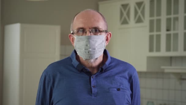Starszy mężczyzna w masce medycznej i patrząc do kamery - Materiał filmowy, wideo